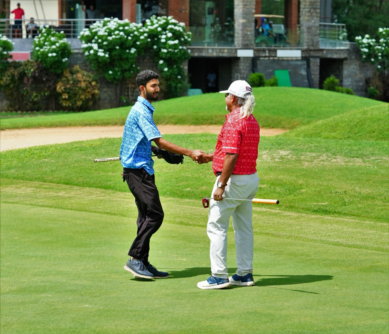 Two golfers shaking hands on a golf course